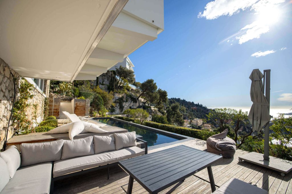 Private terrace with modern garden furniture, infinity pool and spectacular views of the Mediterranean and surrounding hills.