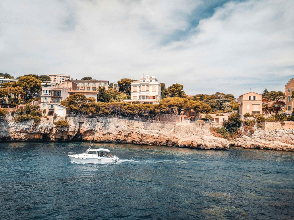 Mediterranean seaside with clifftop villas and motorboats sailing on calm seas. Typical southern French landscape, between coastal charm and Provencal architecture. 