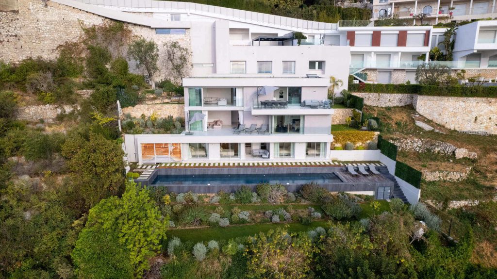 Luxury contemporary villa with infinity pool, spacious terraces and panoramic views, nestled on a hillside on the Côte d'Azur. Modern architecture and exceptional greenery. 
